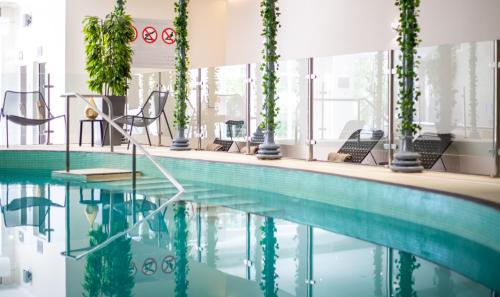 东格林斯特德费尔布里奇皇冠假日酒店&度假村 - 盖特威克的一座带椅子和植物的酒店游泳池