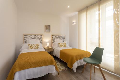 塔皮亚德卡萨列戈Playa Ribeiría apartamento vacacional的一间卧室配有两张床和一张绿色椅子