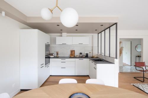 雷恩L'Eden - Appartement familial au pied du Thabor的厨房配有白色橱柜和桌椅