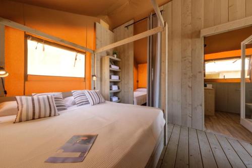 FayónCamping Fayón Fishing的一间卧室配有一张白色的床和橙色的墙壁