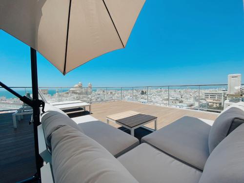 加的斯Skyline - Penthouse with 50m2 private terrace and stunning views的阳台配有桌椅和遮阳伞。