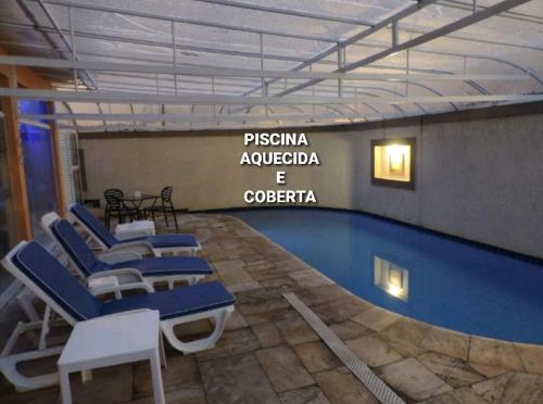 瓜鲁雅Hotel Costa Balena-Piscina Aquecida Coberta的一个带蓝色椅子和标志的游泳池