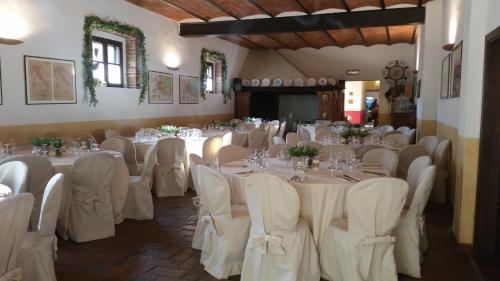 基乌斯迪诺圣嘉嘉诺农家乐的宴会厅配有白色的桌椅