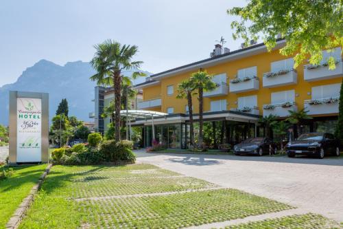 加尔达湖滨坎帕尼奥拉酒店的一座棕榈树和街道的大型黄色建筑