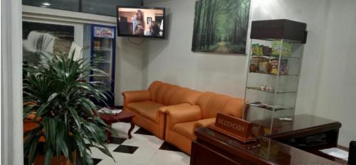 帕斯托Hotel Xilon Resort Plaza的客厅里有一个橙色沙发