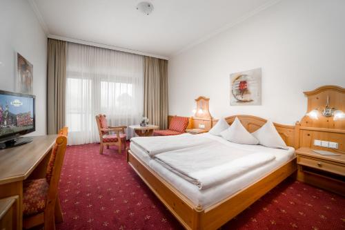 菲根客乐福酒店的酒店客房配有一张床、一张书桌和一台电视。