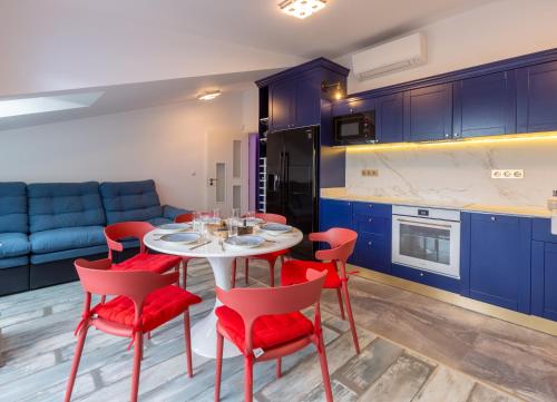 布尔加斯Seaman's house的厨房配有蓝色橱柜、白色桌子和红色椅子