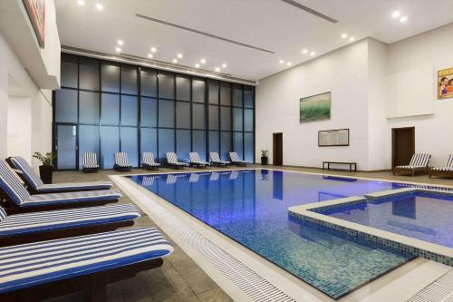 阿吉曼Ramada Hotel & Suites by Wyndham Ajman的大楼内带椅子的大型游泳池