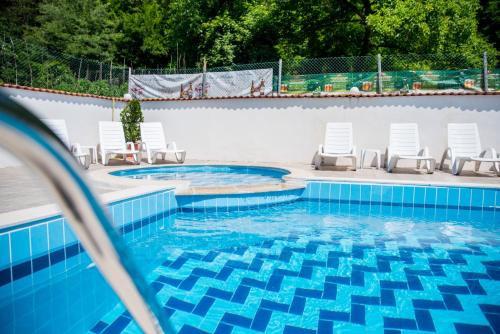 埃伦娜Семеен Хотел Свети Георги的一个带白色椅子和蓝色的游泳池
