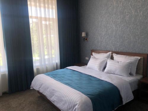 撒马尔罕Sabrina Hotel的一间卧室设有一张带蓝色墙壁和窗户的大床