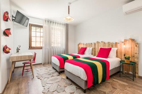 布拉干萨Estrela de Montesinho的一间卧室配有两张床、一张桌子和一台电视。