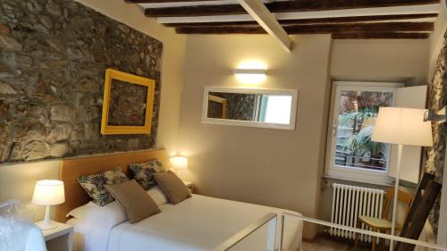 韦尔纳扎Santa Marta Rooms - Via Del Santo 25的卧室配有白色的床和石墙