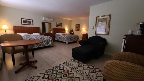 布克塔谢Bouctouche Bay Inn的酒店客房带两张床和一张桌子以及椅子。