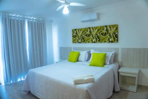 阿拉亚尔达茹达Arraial D'Ajuda, Altos da pitinga ,3 suítes的卧室配有带绿色枕头的大型白色床