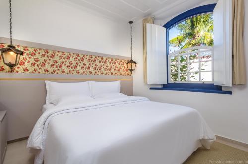 帕拉蒂Pousada Aconchego的卧室配有白色的床和窗户。