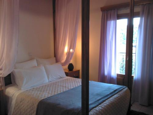 卡尔派尼西翁Menta( Archontiko Machalioti )的一间卧室配有一张带白色床单的床和一扇窗户。