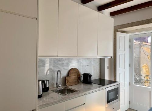 波尔图Oporto Chic&Cozy - São Bento da Vitória的厨房配有白色橱柜和水槽