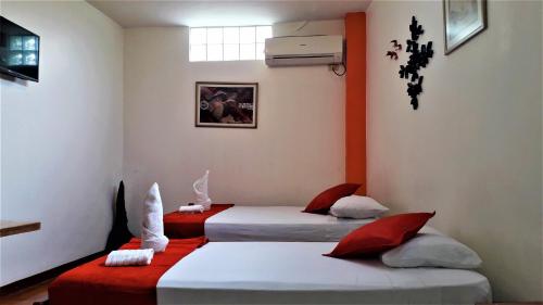 阿约拉港Hostal El Pinzón的红色和白色的客房内的两张床