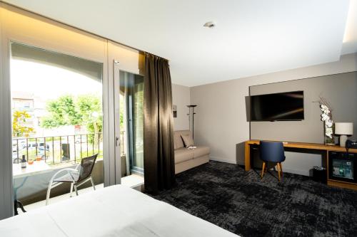 坦耶尔米塔格Fac & Spera -Hôtel & Spa的酒店客房配有一张床、一张书桌和一台电视。