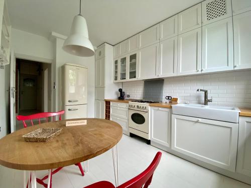 华沙Chic Apartment in vibrant area - National Stadium - Saska Kępa的厨房配有白色橱柜和木桌