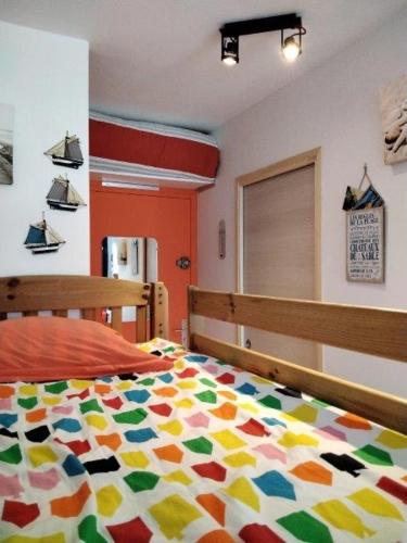 波尔尼谢Charmant studio Bord de mer Plage Ste Marguerite Pornichet的卧室配有色彩缤纷的被子。