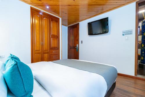 波哥大Ayenda Casa Candilejas的卧室配有一张床铺,墙上配有电视