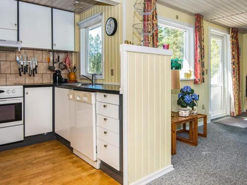 孔斯马克6 person holiday home in R m的厨房配有白色橱柜和墙上的时钟