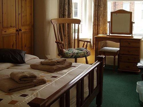 埃克斯茅斯Breken Guest House的一间卧室配有一张床、一把椅子和镜子