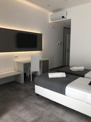 圣玛丽亚德尔西德Sesto Senso Home的一间卧室配有两张床、一张桌子和一台电视。