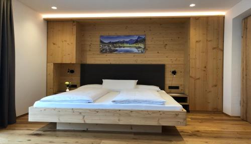 布鲁尼科B&B Obermair的一间卧室设有一张带木墙的大床