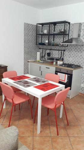 圣雷莫MAX and SUN parking privato nel prezzo的厨房配有白色的桌子和红色的椅子