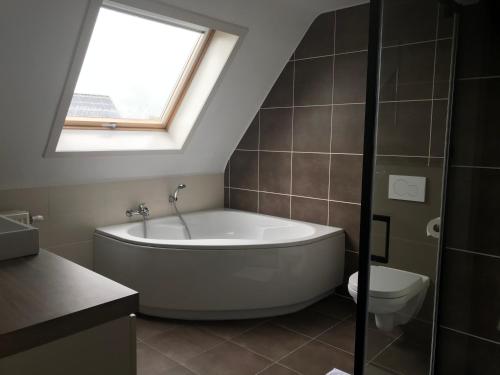 德哈恩Huis Marlin的带浴缸、卫生间和窗户的浴室