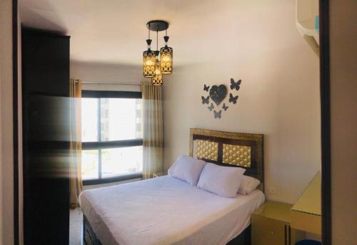 塞得港بورتوسعيد Porto Said的一间卧室配有一张带吊灯和窗户的床。