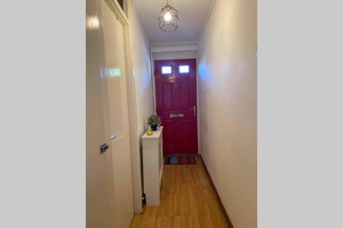 伦敦Beautiful Large ROOM in London Flat的一条带红色门和白色墙壁的走廊