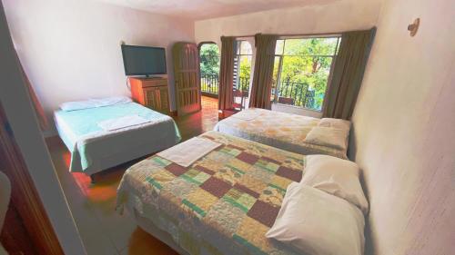 帕纳哈切尔Hotel Posada Don Carlos的酒店客房设有两张床和电视。