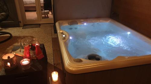 热拉梅AU NID COSY D'ISA A GERARDMER VOSGES - Spas privatifs的一个带桌子和蜡烛的客房内的按摩浴缸
