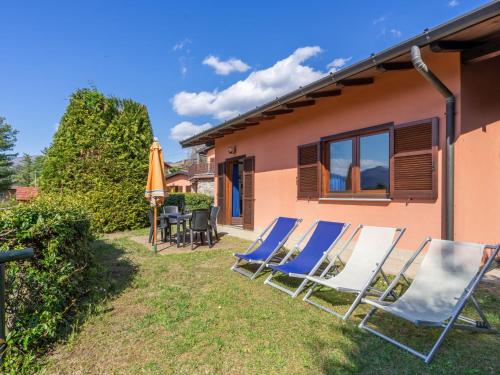 勒威诺Holiday Home Residenza Agrifoglio-12 by Interhome的院子里一群草坪椅和一把伞