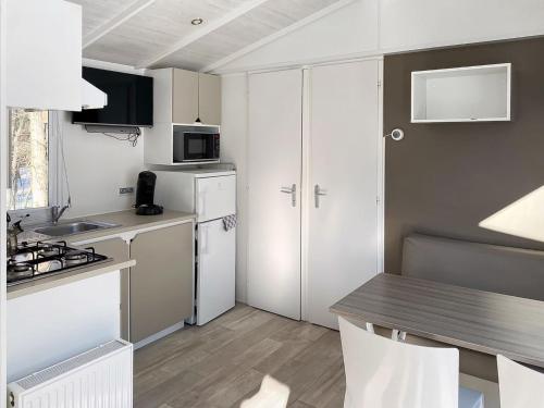 斯欣费尔德Holiday Home De Brenkberg-1的厨房配有白色橱柜和桌椅