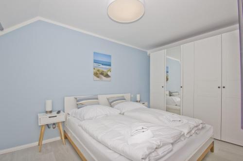 格罗斯齐克Ferienwohnung mit Meerblick und Gartennutzung - Haus Inselwind FeWo MEERstrand的一间卧室配有一张带白色床单的大床