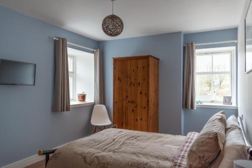 德里门Altquhur Byre的一间蓝色卧室,配有床和2个窗户
