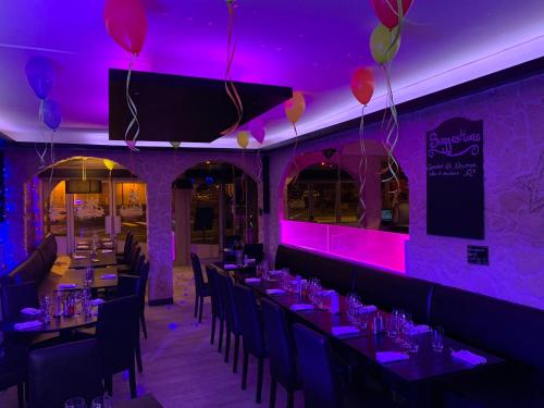 伊苏丹La Locomotive的一间拥有紫色灯光和桌椅的用餐室