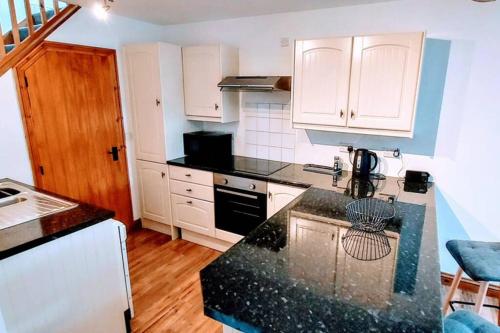 图克斯伯里Town centre cottage的厨房配有白色橱柜和黑色台面