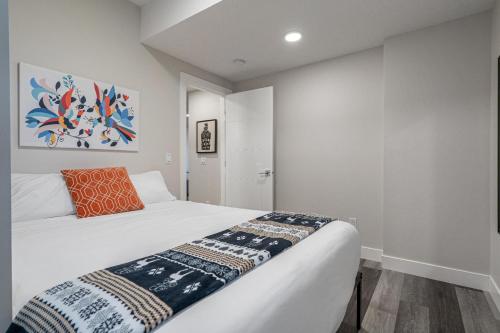 卡尔加里Contemporary 1br Home Full Kitchen Smarttv的卧室配有白色床和橙色枕头