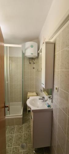 拉布Adria Arba Apartments的浴室配有水槽、淋浴和浴缸。