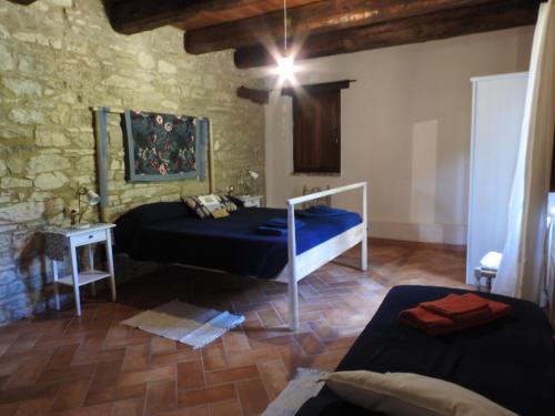 Monte Grimano TermeCasale Le Fontanelle的一间卧室设有两张床和石墙
