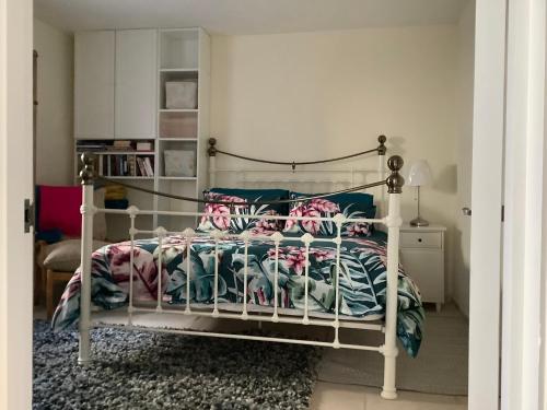 滨海韦斯顿Garden apartment的卧室配有白色的床、色彩缤纷的毯子和枕头。