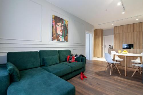 利沃夫AUSTRIAN APART HOTEL的一间带绿色沙发的客厅和一间厨房
