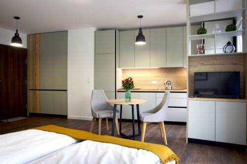 波兹南Essence Apartments Sapphire的一间卧室配有一张床,厨房配有桌椅