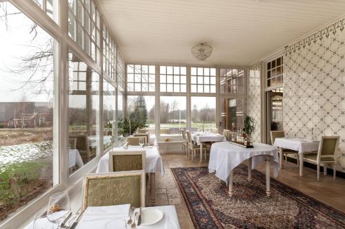 韦斯特莱瓦斯特勒庄园度假酒店的餐厅设有桌椅和大窗户。