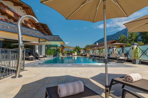 卡顿巴赫珀斯特酒店的一个带椅子和遮阳伞的度假村游泳池